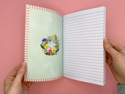 Inside front cover design. Stripy border with the spring wreath in the middle. Wreath includes daffodils, tulips, bluebells, crocuses, green foliage, bees and a blue tit bird. Same design on the inside back cover.